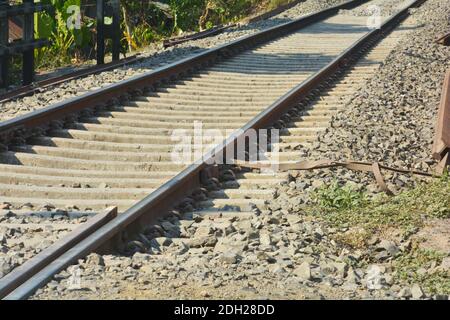 Primo piano di linee ferroviarie, binari ferroviari, ferrovia di Indian Railway con ringhiere ferroviarie, pietre su una ferrovia che attraversa una strada, focalizzazione selettiva Foto Stock