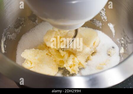 Miscelare il burro e lo zucchero in macchina di miscelazione, in casa di panificio, close up Foto Stock