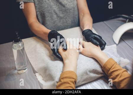 Estetista che applica la crema sulle mani del cliente. Salone di bellezza. Massaggio mani. Manicure al salone. Concetto di manicure spa. Mani femmina wi Foto Stock