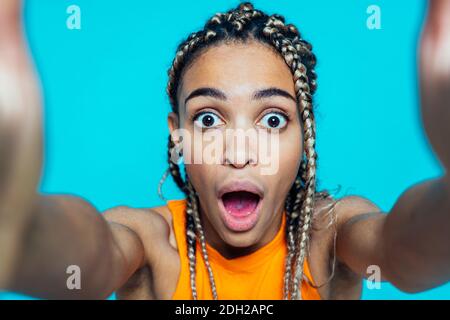 Bella ragazza con i pigtail che fanno festa su un colore blu sfondo Foto Stock