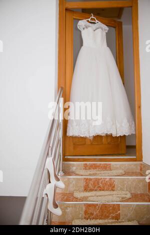 Un colpo verticale di un abito da sposa bianco appeso dentro parte anteriore di una porta Foto Stock