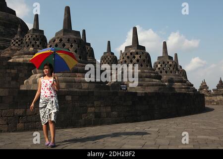 Giovane visitatore con un ombrello nel Borobudur Temple nel centro di Giava, Indonesia. Foto Stock