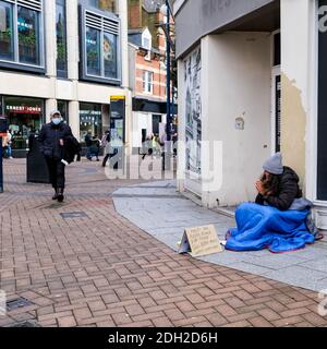 Kingston London, dicembre 09 2020, senzatetto povera donna seduta su un marciapiede in UNA porta del negozio che prega di denaro Foto Stock