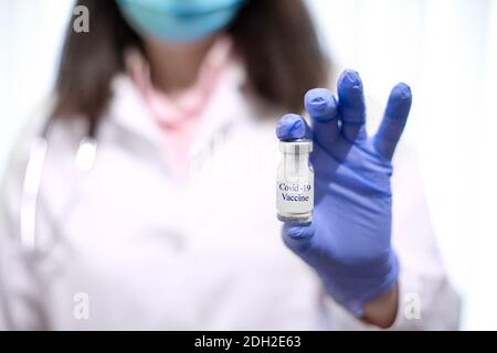 Medico femminile con stetoscopio su siringa con supporto per spalla e vaccino COVID-19. Concetto sanitario e medico. Foto Stock