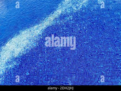 Piscina d'acqua con increspature e rifrazioni su piastrelle blu Foto Stock