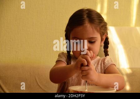 Carina bambina sta giocando e ride mentre impastando l'impasto in cucina. Foto Stock