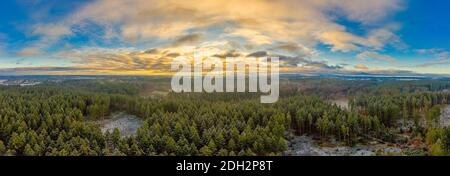 Vista panoramica aerea su un'ampia foresta con il sole sotto il sole, coperto da nuvole di luce Foto Stock