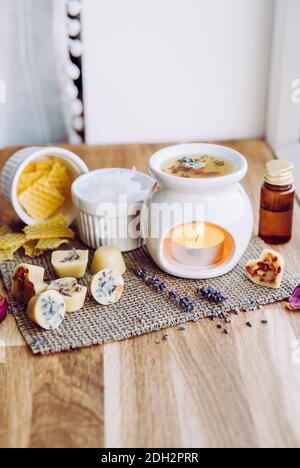 Usando la mini cera casalinga fonde nel diffusore di lampada di aromaterapia al concetto domestico dell'interno. Scioglie gli ingredienti per preparare la cera d'api greggia, solida Foto Stock