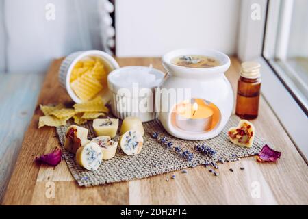 Usando la mini cera casalinga fonde nel diffusore di lampada di aromaterapia al concetto domestico dell'interno. Scioglie gli ingredienti per preparare la cera d'api greggia, solida Foto Stock