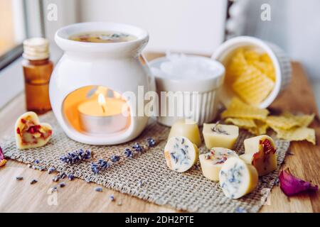 Usando la mini cera casalinga fonde nel diffusore di lampada di aromaterapia al concetto domestico dell'interno. Scioglie gli ingredienti per preparare la cera d'api greggia, solida Foto Stock