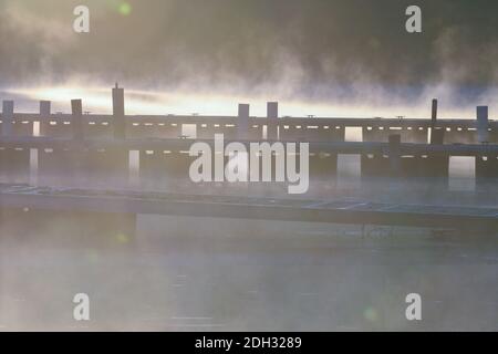 Molo delle barche all'alba con sollevamento della nebbia dal lago tranquillo Acqua Foto Stock