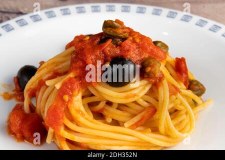 Spaghetti alla Puttanesca, con pomodoro, olive, capperi e acciughe Foto Stock