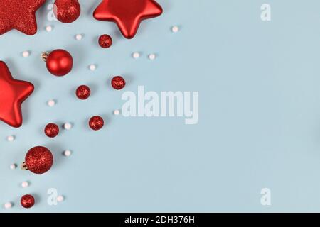 Rosso albero di Natale baubles a forma di palle e stelle e ornamenti di palla di neve bianca in un angolo di sfondo azzurro con spazio di copia vuoto Foto Stock