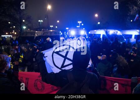 Varsavia, Varsavia, Polonia. 9 Dic 2020. Un attivista del clima detiene una bandiera della ribellione estinzione di fronte a un cordone di agenti di polizia durante una protesta contro il cambiamento climatico il 9 dicembre 2020 a Varsavia, Polonia. Alcune centinaia di manifestanti si sono riuniti davanti alla cancelleria del primo ministro polacco, Mateusz Morawiecki, per protestare contro la mancanza di azione da parte del governo per raggiungere la neutralità del carbonio entro il 2030 e il veto sul bilancio dell'Unione europea, che potrebbe aiutare la Polonia a raggiungere l'obiettivo. Credit: Aleksander Kalka/ZUMA Wire/Alamy Live News Foto Stock