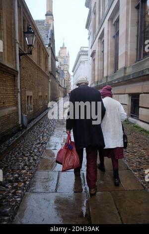 Cambridge UK Dicembre 2020 Vista posteriore di una coppia più anziana Camminando attraverso la strada del passaggio della Camera del Senato nel centro Della città di Cambridge con una pioggia fredda Foto Stock