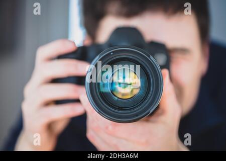 Fotografo al lavoro: L'uomo si trova dietro una fotocamera professionale su un treppiede, facendo foto Foto Stock