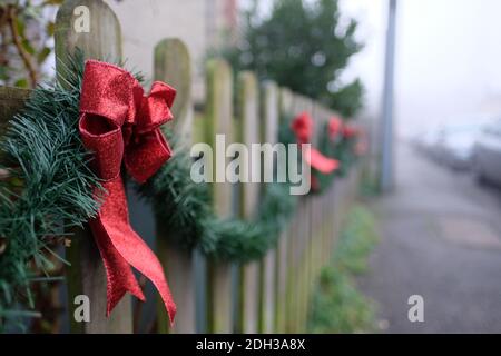 Recinzione in legno decorata in stile festivo con nastri rossi con l'avvicinarsi del periodo di dicembre e natale Foto Stock