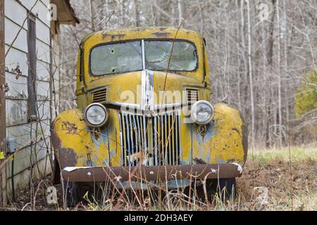 Una vecchia automobile abbandonata di Rusty si siede da sola in UN campo Foto Stock
