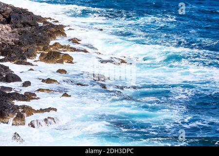 Onde che colpiscono le rocce della riva del mare Foto Stock