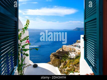 Vista da una finestra che si affaccia sul mare, la caldera e il villaggio imbiancato di Oia sull'isola di Santorini, Grecia. Foto Stock