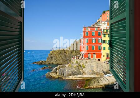 Vista attraverso una finestra aperta del villaggio italiano di Riomaggiore, parte delle cinque Terre sulla costa ligure del Nord Italia Foto Stock