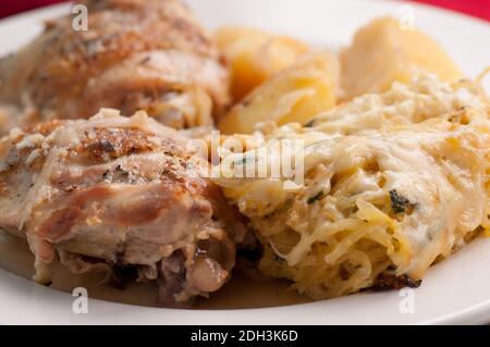 cosce di pollo con gratin di zucca al forno e patate Foto Stock