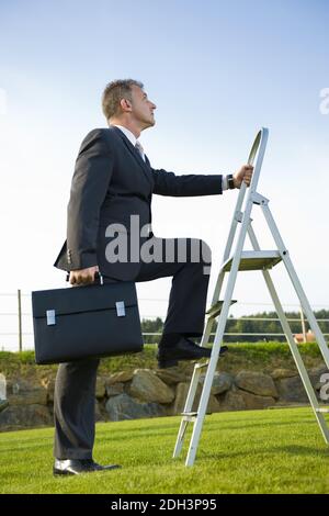 Geschäftsmann, 40 Jahre, klettert, Leiter, nach oben, Karriere, Karrieresprung, Karriereleiter, signor:Sì Foto Stock