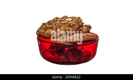 Biscotti appetitosi in un piatto rosso, biscotti di arachidi isolati su bianco, primo piano Foto Stock