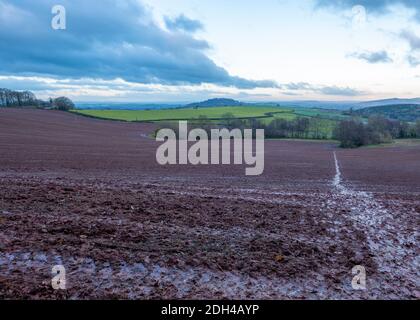 Percorso attraverso un campo fangoso in inverno sotto nuvoloso coperto cielo Foto Stock