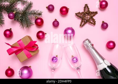 Decorazioni natalizie, champagne, abete e confezione regalo su sfondo rosa pastello. Il concetto di celebrare il nuovo anno e il Natale. Vista dall'alto. Foto Stock