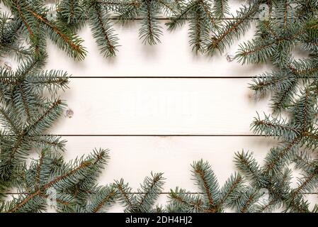 Cornice Natale creativa realizzata in rami di abete su tavolo bianco con spazio per la copia del testo. Concetto di Natale e inverno. Foto Stock