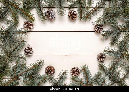 Cornice Natale creativa realizzata in rami di abete e coni di pino su tavolo bianco con spazio per la copia del testo. Concetto di Natale e inverno. Foto Stock