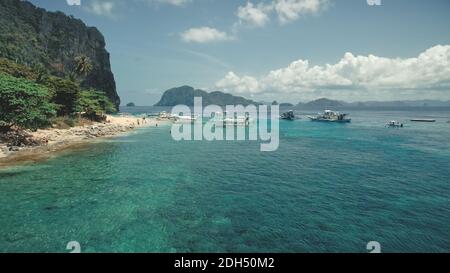 Crociera passeggeri barche con turisti alla costa di resort tropicale in tour dell'Arcipelago delle Filippine, isola di El Nido. I viaggiatori si rilassano e si godono la loro vacanza in spiaggia e in acqua nella calda giornata di sole Foto Stock