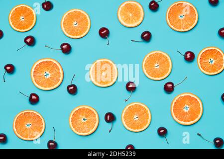 Fette di arancia e ciliegie dolci su sfondo blu Foto Stock