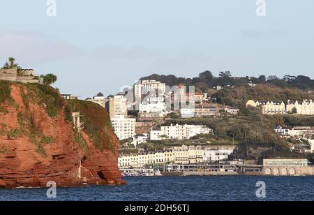 Torquay / Torbay, Devon, Inghilterra: Scogliere di arenaria rossa in primo piano (a sinistra) e la località turistica di Torquay sullo sfondo. Foto Stock