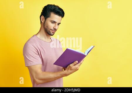 Bel giovane uomo in abiti casual che legge un libro Foto Stock