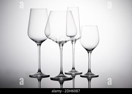 Una foto di un set di vetro - verricelli vuoti, flauto di champagne e vodka vetro sulla superficie bianca con ombre Foto Stock