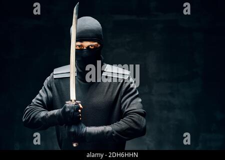 Combattere il ninja con una spada su sfondo nero Foto Stock