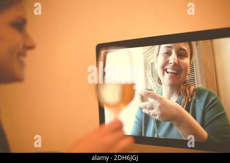 Donne allegre che bevono vino tramite chat video