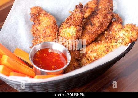 polli o strisce con salsa piccante di peperoncino e bastoncini di verdure Foto Stock