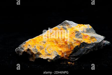 Arancione brillante realgar minerale con stibnite e granito Foto Stock