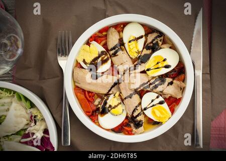 Una ciotola di insalata con pepe rosso arrosto, pancia di tonno e uovo cotto Foto Stock