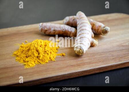 Radice curcuma e polvere di spezie su un tagliere Foto Stock