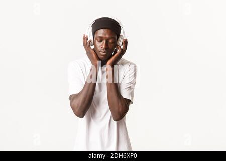 Ritratto di un ragazzo rilassato afro-americano sognante, godendo di musica in cuffia con occhi chiusi, soddisfazione da sostantivo Foto Stock