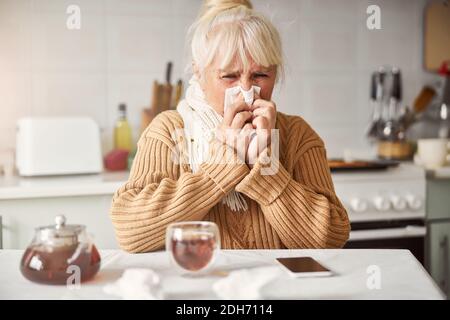 Donna anziana che ha naso che cola e non si sente bene Foto Stock