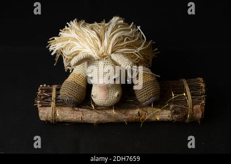 Un giocattolo a cavallo amigurumi uncinetto con una pila decorativa di legno su sfondo nero Foto Stock