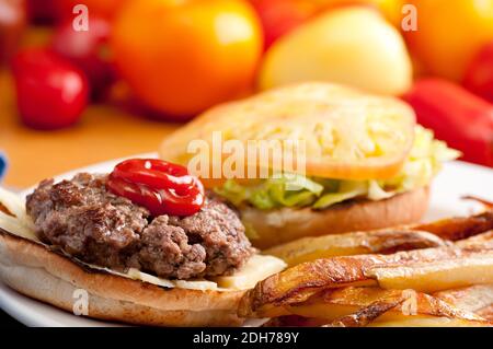 hamburger biologico, carne etica con patatine fritte tagliate a mano e pomodori di primo piano, farina da fattoria a tavola completa Foto Stock