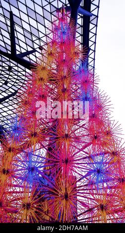 Vista ad angolo basso da un albero di Natale elettrico in rosa, illuminato di giorno di fronte a un centro commerciale su Orchard Road, Singapore. Foto Stock