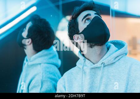 Un colpo di un uomo in una maschera medica con il riflesso nello specchio Foto Stock