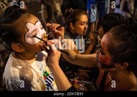 Ragazze che ottengono i loro volti dipinte sulla notte di Halloween su Nguyen Hue Walking Street, ho Chi Minh City, Vietnam Foto Stock